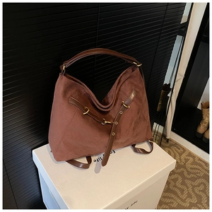 Detail of chocolate brown suede tote bag featuring smooth leather straps and gold metal hardware
