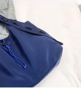Detail of lightweight navy blue nylon tote bag with button accents on white fabric