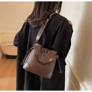 Detail view of dark brown litchi leather bucket bag with contrast stitching and wide strap