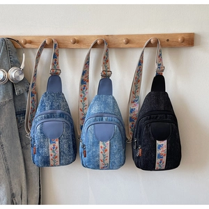 Detail of washed denim crossbody chest bags with colorful floral embroidery straps