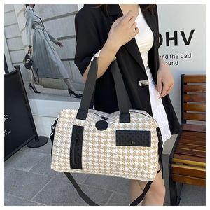Detail of houndstooth travel bag with large side zipper pocket and black top handles