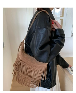 Dettaglio della borsa a tracolla marrone in camoscio con frange boho indossata dalla modella