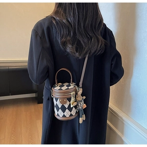 Detail of retro quilted cylinder bucket bag with tricolor stitching and rabbit charm