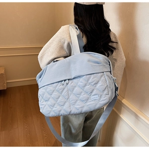 Detail of light blue quilted travel bag with diamond stitching and front zipper pocket
