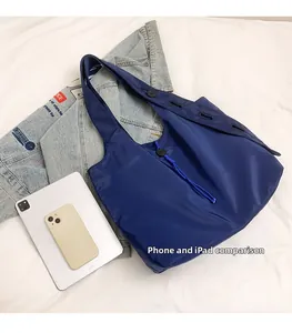 Detail view of a large navy blue tote bag showing its storage capacity with an iPad and phone