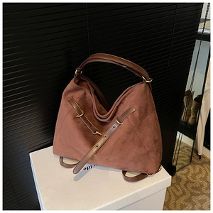 Close-up of matte dark brown tote bag with gold metal rings and leather strap details