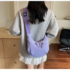 Detail view of purple crescent crossbody bag with double zippers and adjustable wide strap
