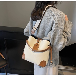 Detailed view of beige bucket bag with lychee texture and brown leather accents