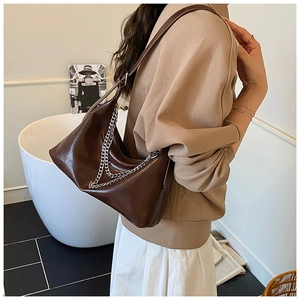 Detail of dark brown leather shoulder bag featuring decorative silver double chains