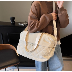Detail of quilted beige tote bag showing high-capacity design and nylon shoulder strap
