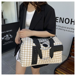 Detail of houndstooth travel bag with metal chains and adjustable black strap