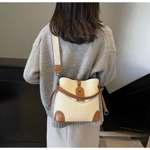 Detailed back view of a person wearing a beige and brown leather bucket bag with wide strap