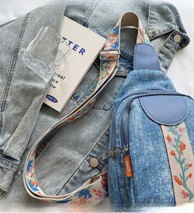 Detail of blue denim crossbody chest bag with colorful jacquard embroidered wide strap
