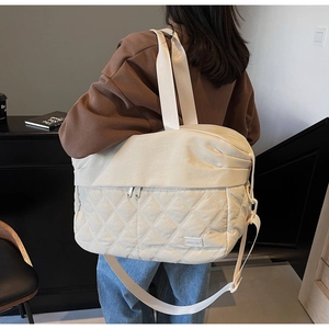Detailed close-up of a cream quilted travel bag showing textured stitching and handle