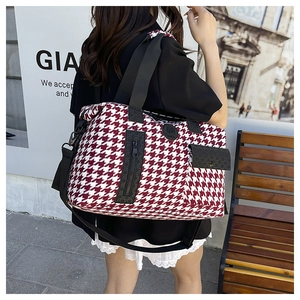 Detail of red houndstooth travel bag with adjustable strap and small side pouch