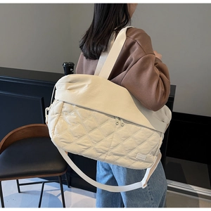 Macro detail of beige quilted travel bag featuring diamond texture and dual zippers