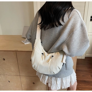 Detail of off-white crescent crossbody bag with double drawstring zipper pockets