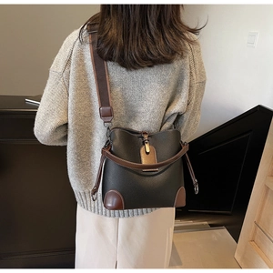 Detail view of a vintage leather bucket bag with pebble texture and wide woven shoulder strap