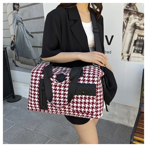 Detail view of large red houndstooth travel bag with black straps and side zip pocket