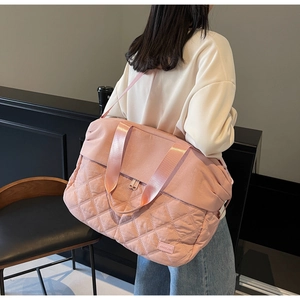 Detailed side view of pink quilted travel bag with large capacity and woven shoulder strap