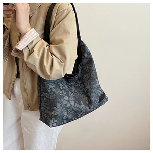 Detail of floral tote bag with high-quality fabric texture and black leather shoulder strap