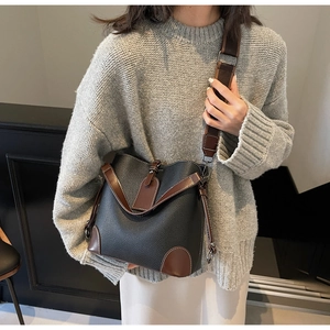 Detailed view of black litchi leather bucket bag with brown trim and nylon strap