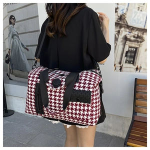 Detail of red houndstooth travel bag with reinforced black handles and side pocket