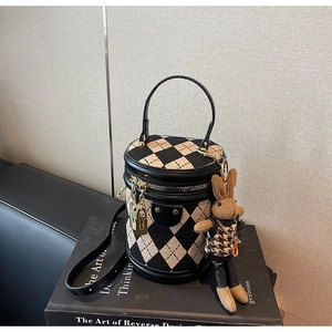 Close-up of argyle cylinder bag with gold clasp and a cute rabbit charm detail
