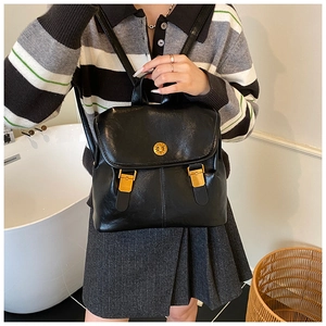 Close-up of black leather backpack featuring a vintage gold twist lock and flap design