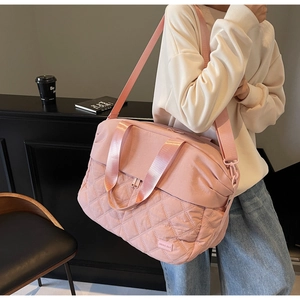 Pink large travel bag with quilted details and adjustable strap shown in lifestyle setting