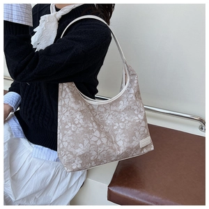 Close-up of a large floral tote bag in beige fabric with white faux leather trim details