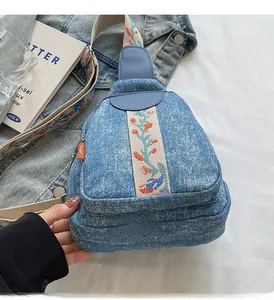 Detailed view of floral embroidery on denim crossbody bag with high quality stitching
