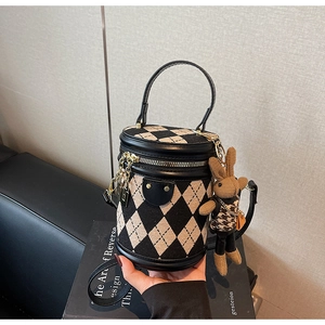 Close-up of quilted cylinder bag with cute brown plush rabbit charm and gold hardware