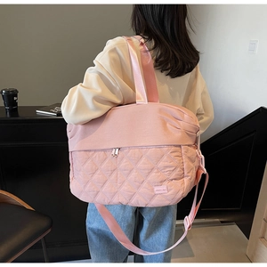 Detail view of pink quilted travel tote showing diamond texture and wide straps