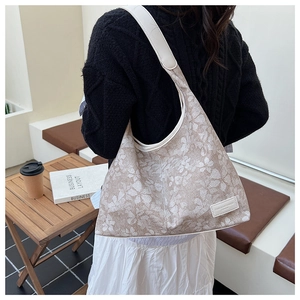 Detailed side view of the large floral tote bag on model in a cozy cafe setting