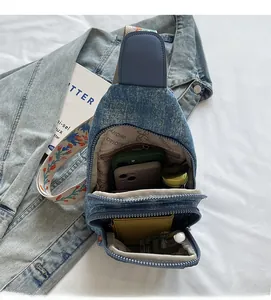 Detail view of denim crossbody bag with ethnic embroidered strap and large main compartment