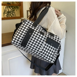 Detail of large houndstooth travel bag showing side pockets and wide shoulder strap
