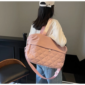 Detailed side view of large pink quilted travel bag with adjustable strap on model