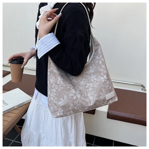 Detail view of floral canvas tote bag with shoulder strap in a cozy cafe setting