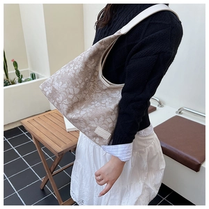 Detail of beige floral jacquard tote bag featuring premium texture and brand label