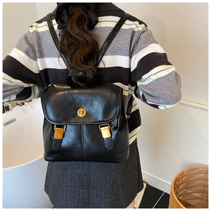 Detail of vintage black leather backpack showing gold metal hardware and buckle closure