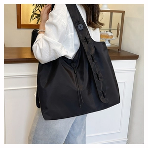 Detail of adjustable shoulder strap buttons and side drawstring on large black hobo bag