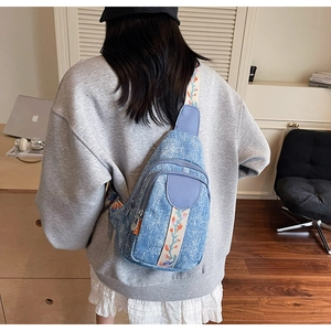 Detailed embroidery of colorful flowers on wide denim crossbody bag shoulder strap