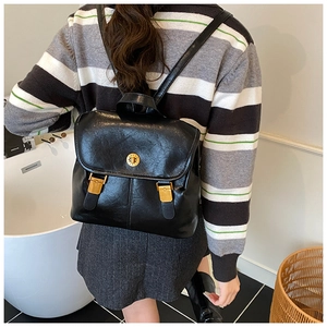 Close-up of black glossy leather backpack featuring vintage gold circular twist lock