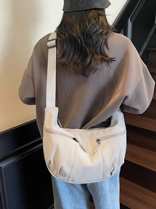 Minimalist beige dumpling shoulder bag made of lightweight nylon with adjustable strap