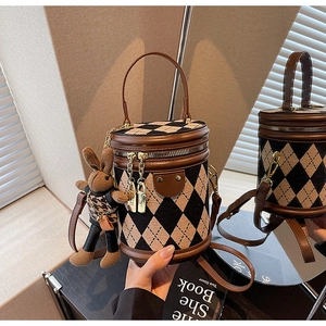 Detail of checkered barrel bucket bag with gold zippers and brown rabbit charm
