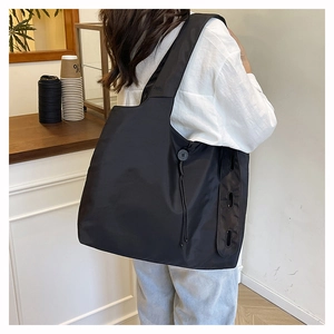 Detail of drawstring adjustment and reinforced eyelets on the black nylon tote bag