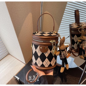Detail of quilted barrel bag with brown leather trim and cute rabbit doll keychain charm
