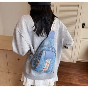 Light blue denim chest bag featuring dual zippers and floral embroidered wide strap detail