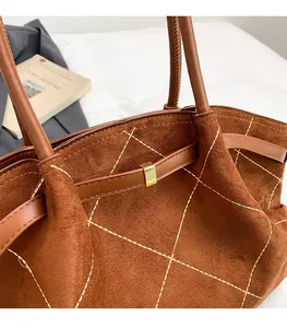 Detail of brown quilted suede tote bag with metal buckle and spacious interior